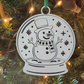 White snow globe ornament with a snowman design on a Christmas tree.