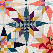 Four clear quilting templates with printed markings are arranged on a colorful geometric quilt. A spool of purple thread and gold scissors sit nearby on the quilt.